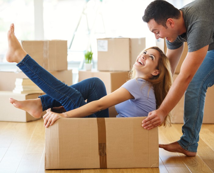 Man pushing woman sitting in moving box