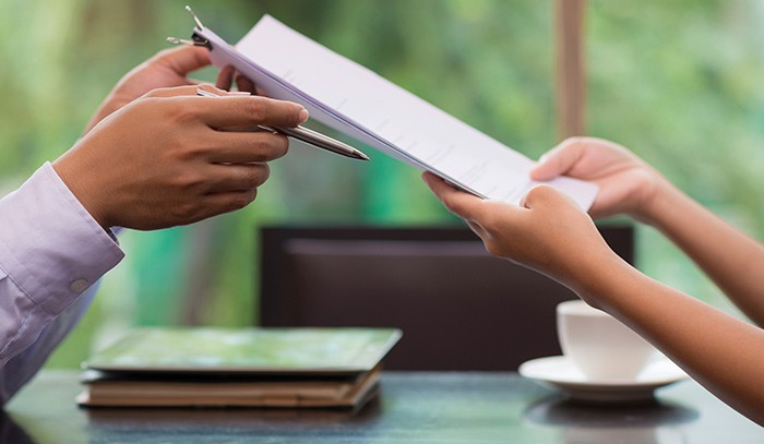 Hands exchanging paperwork to be signed