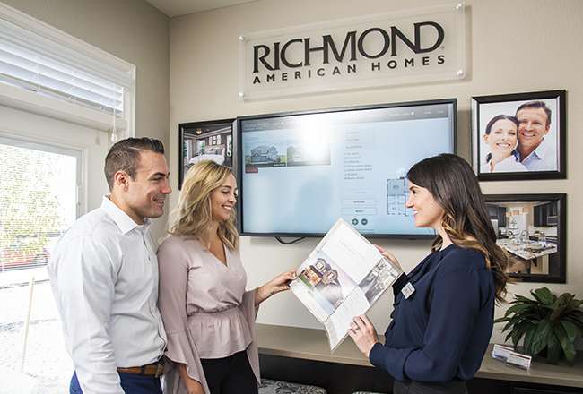 Sales associate handing brochure to homebuyers