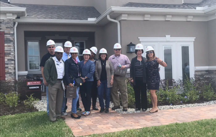 Hard-hat home tour attendees posing in front of sales center