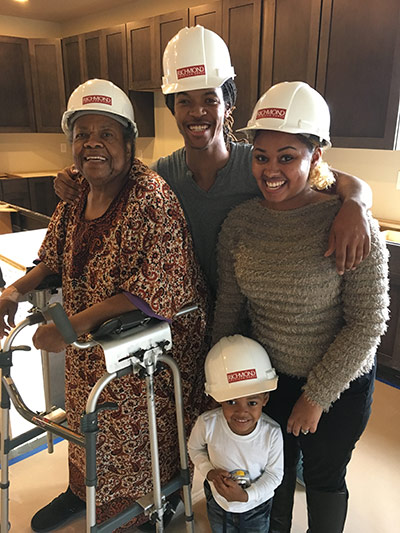 Child, parents and grandmother wearing hardhats while standing in kitchen 