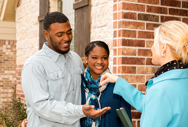 Agent handing house keys to happy couple