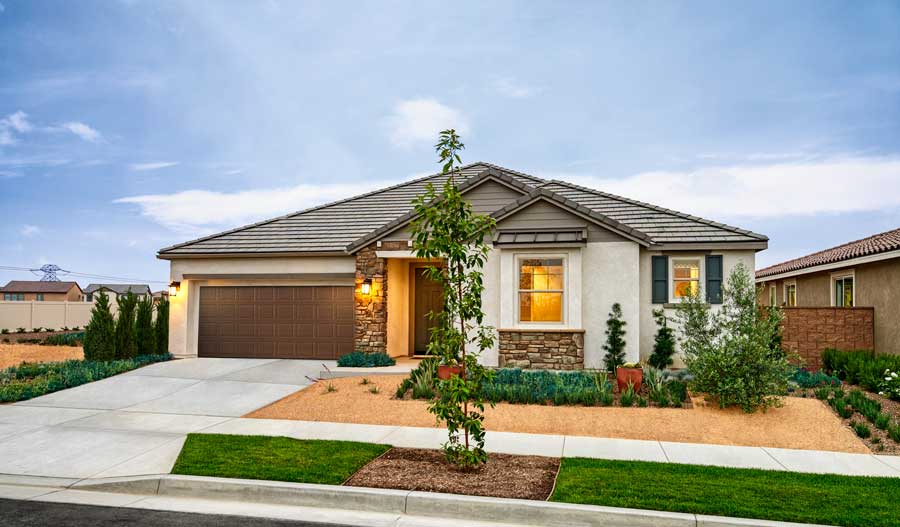 The exterior of the home, showing a two car garage, covered entry, two large windows at the front of the home, and a landscaped yard