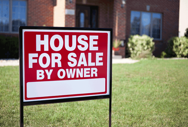 Front lawn of home with s"House for Sale by Owner" sign