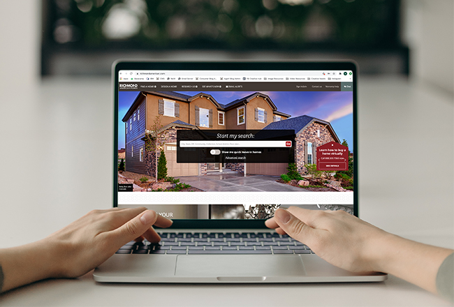 Hands typing on laptop displaying Richmond American's homepage