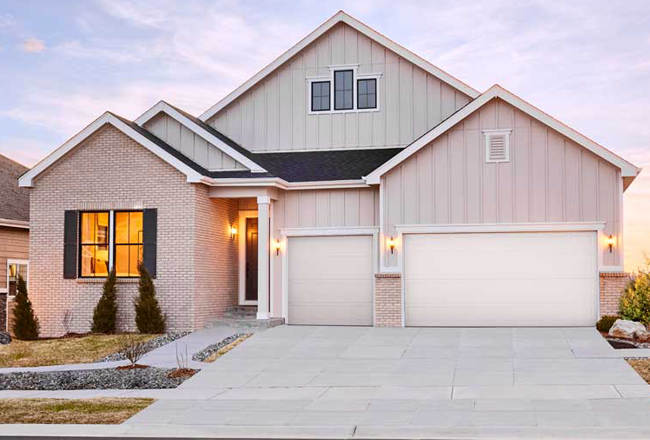 The exterior of a ranch-style home, with a three car garage, covered entry, and grassy front yard.