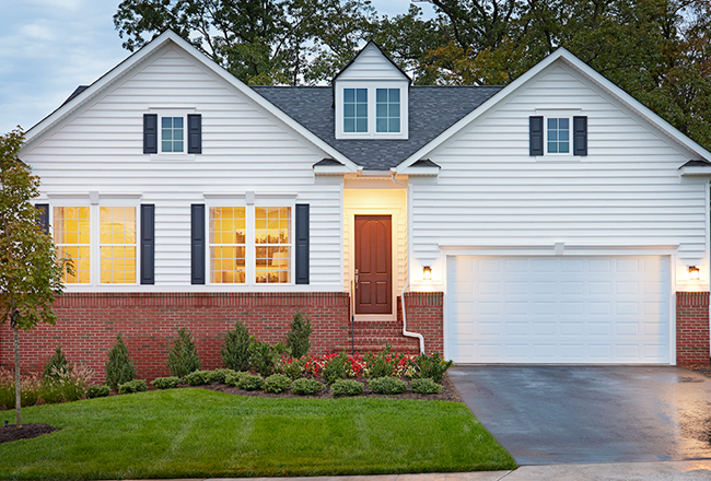 The exterior of a ranch-style home, with stairs leading up to the covered entry, with a two car garage and gassy front yard