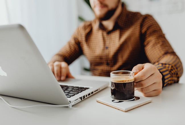 Man looking at computer screen while enjoying a cup of coffee