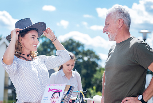 Woman with hat talking to man at yard sale