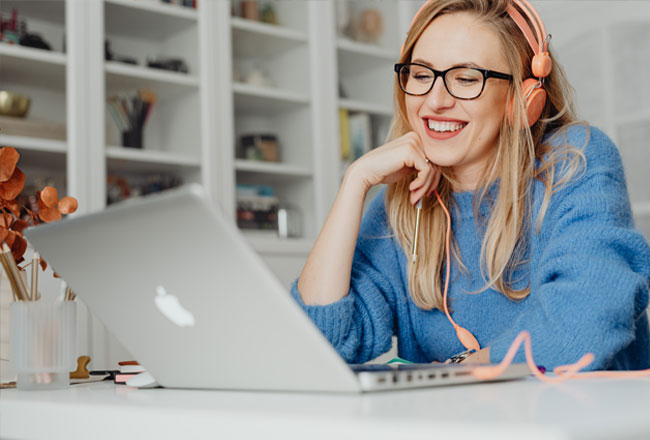 Smiling woman wearing headphones, looking at laptop