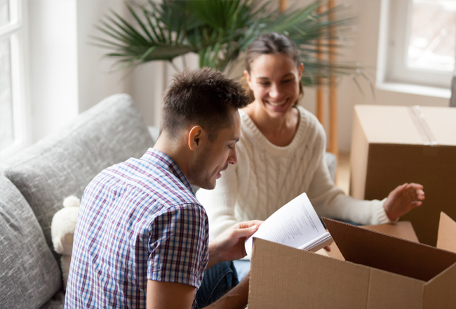 Couple sitting on sofa in front of moving box