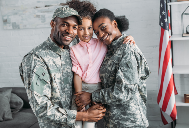 Couple in army uniforms holding their daughter