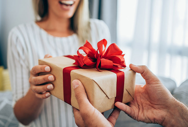 Real estate agent handing a wrapped closing gift gift to a buyer