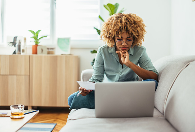 Woman at computer sitting on couch researching real estate