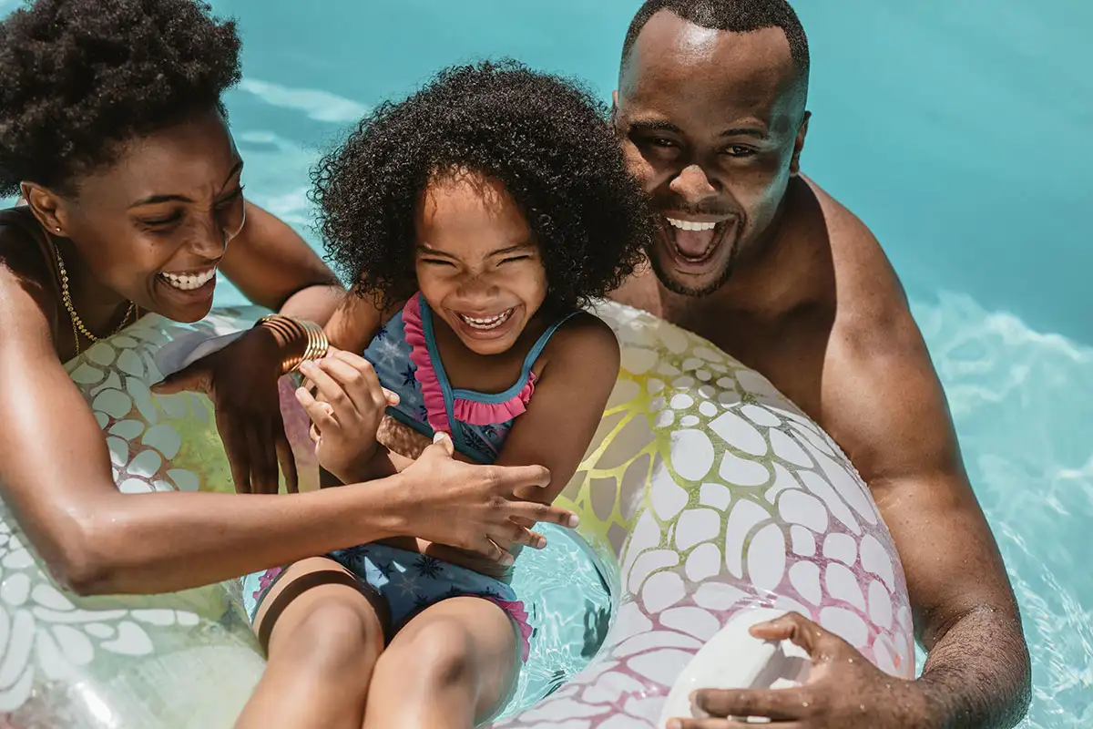Parents holding child sitting in tube in swimming pool