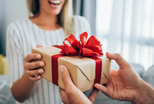 Real estate agent handing a wrapped closing gift gift to a buyer