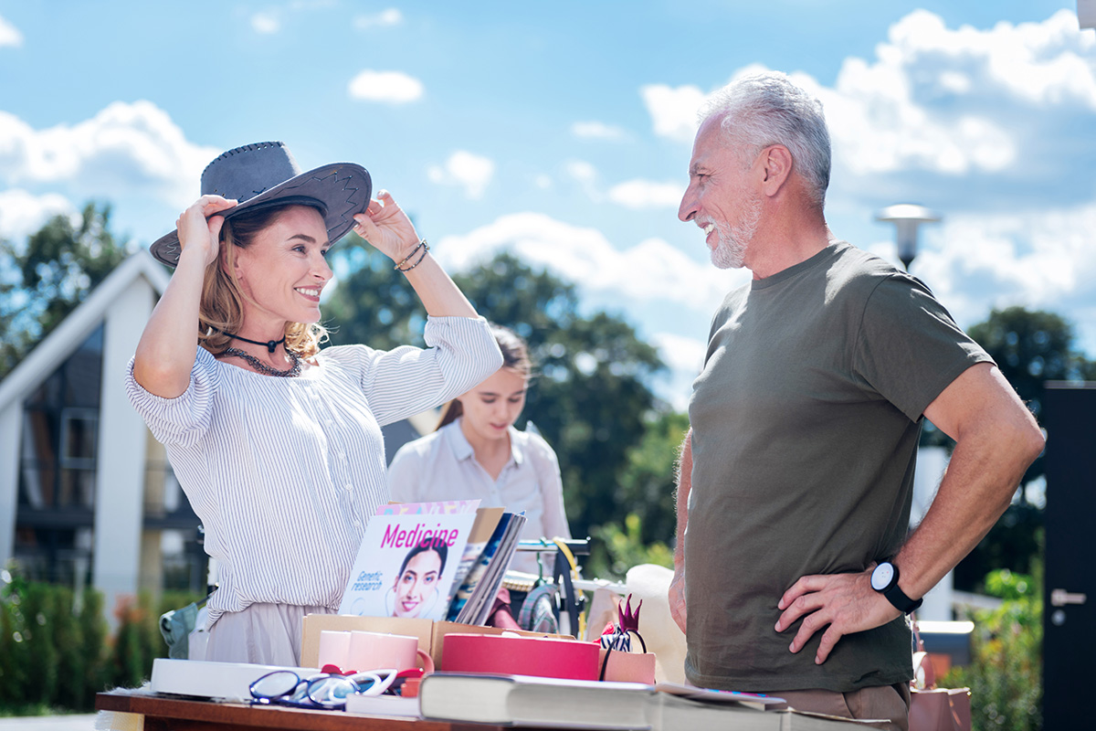 Woman trying on hat at yard sale