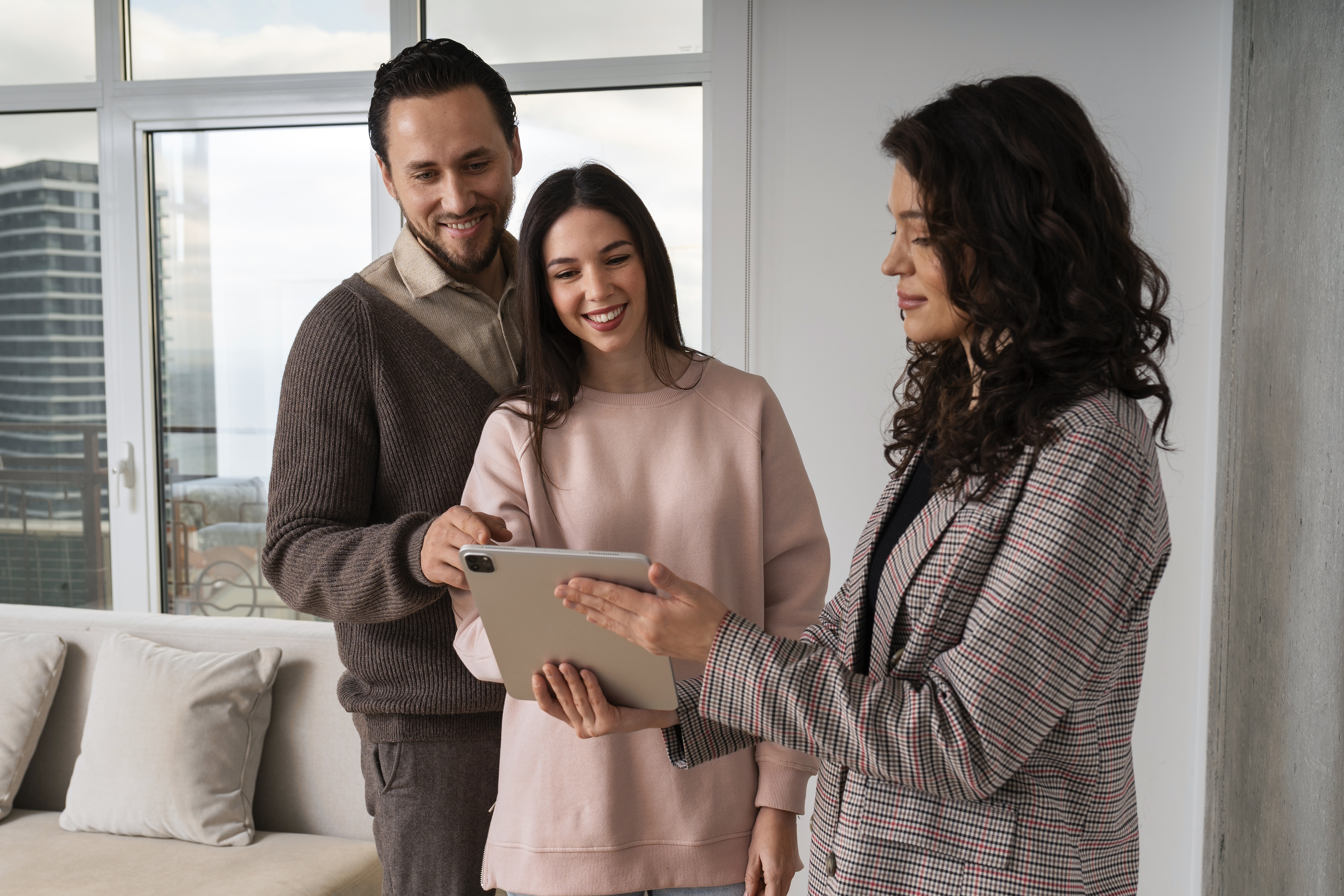 A homebuyer couple looking at documents on a tablet with their real estate agent