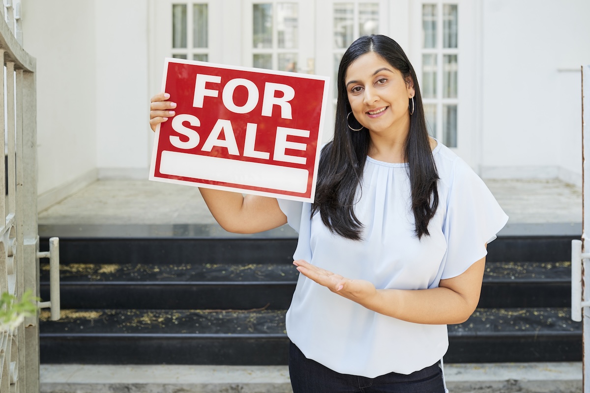 Real estate agent holding a FOR SALE sign