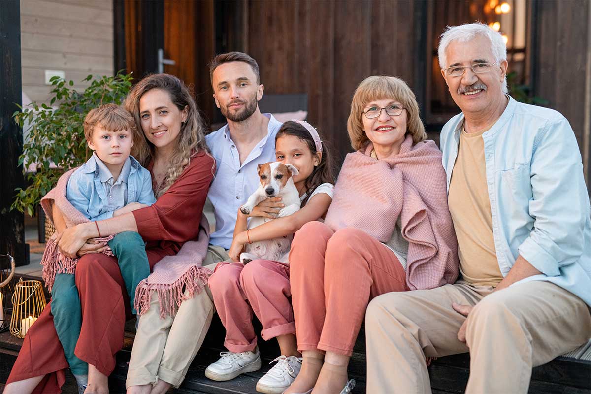 Three generations of a family sitting in front of a house