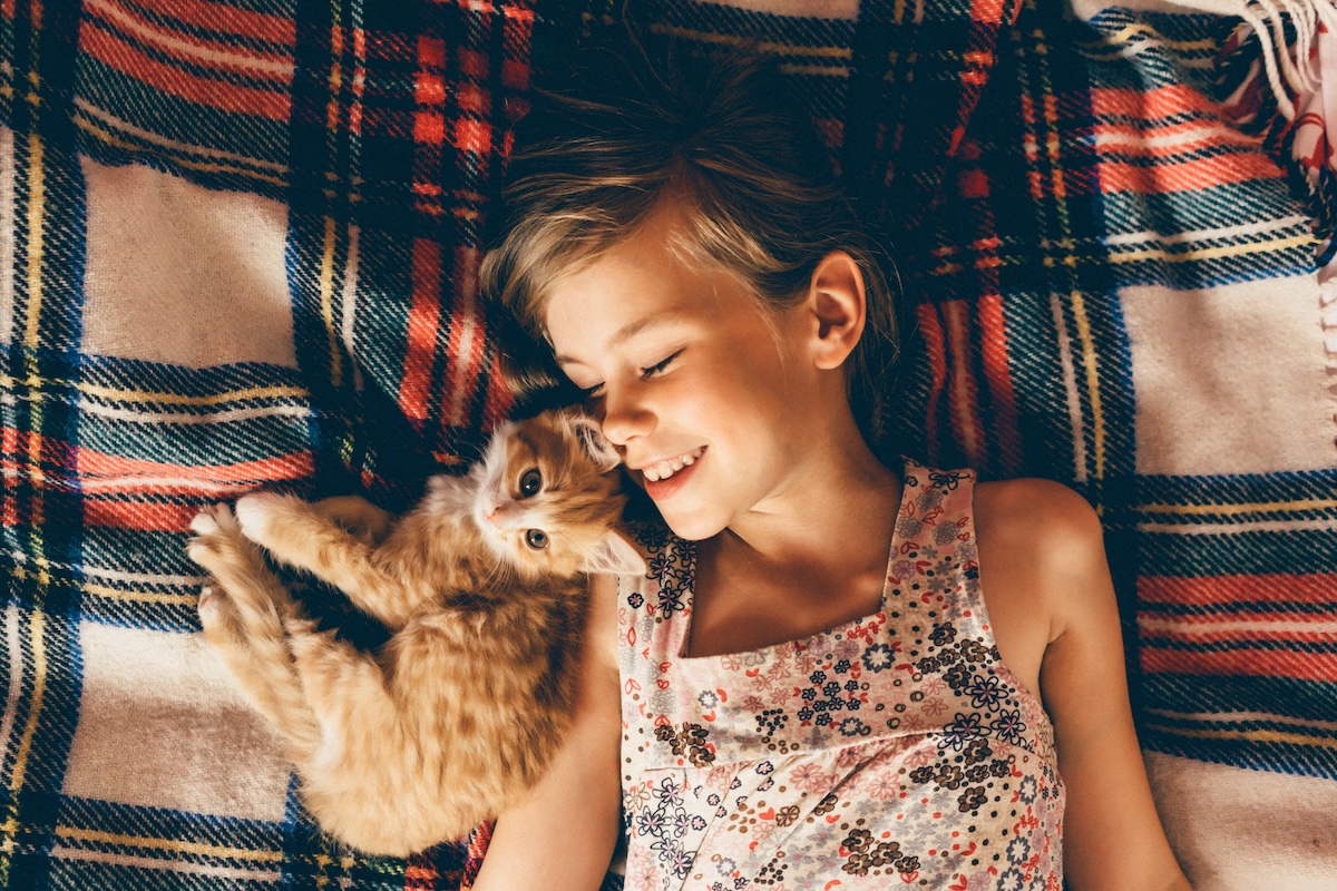 A young girl laying in bed with her pet kitten