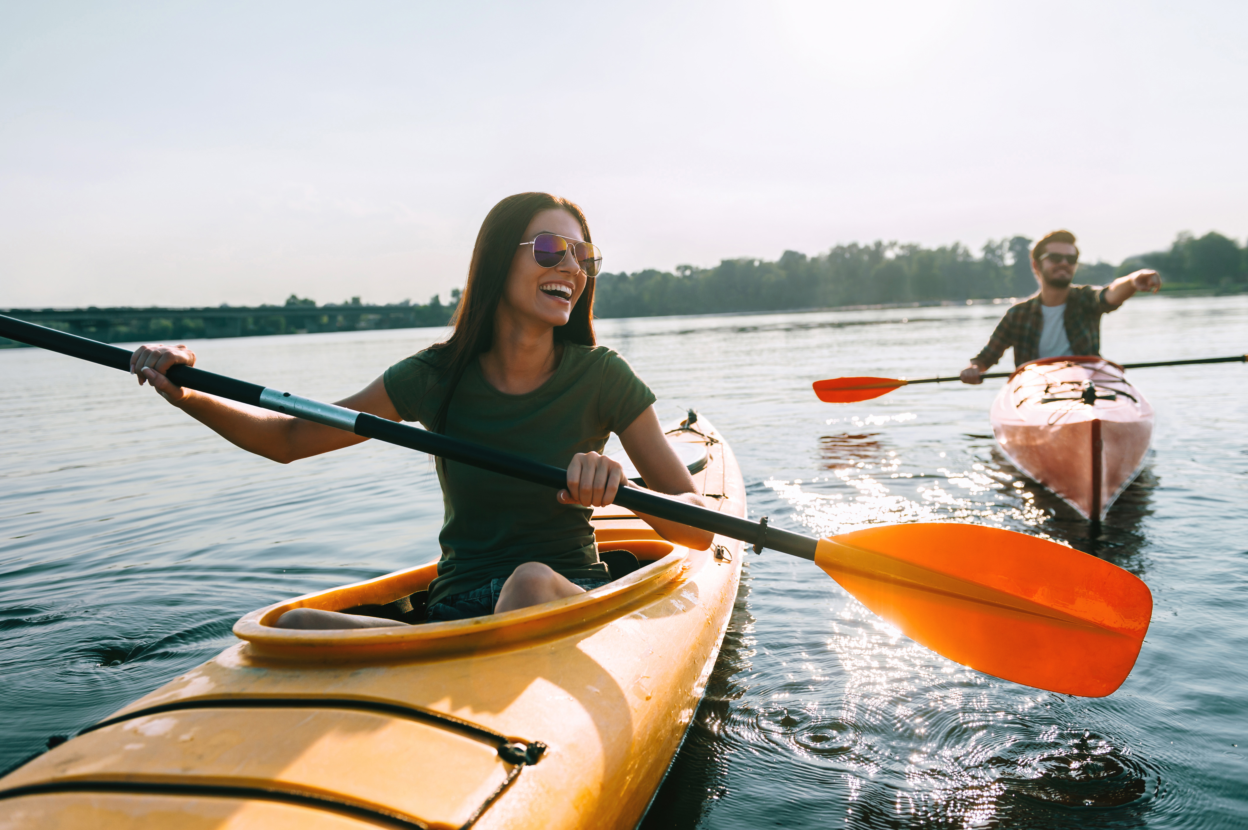 Young couple in canoes in a natural body of water on a sunny day