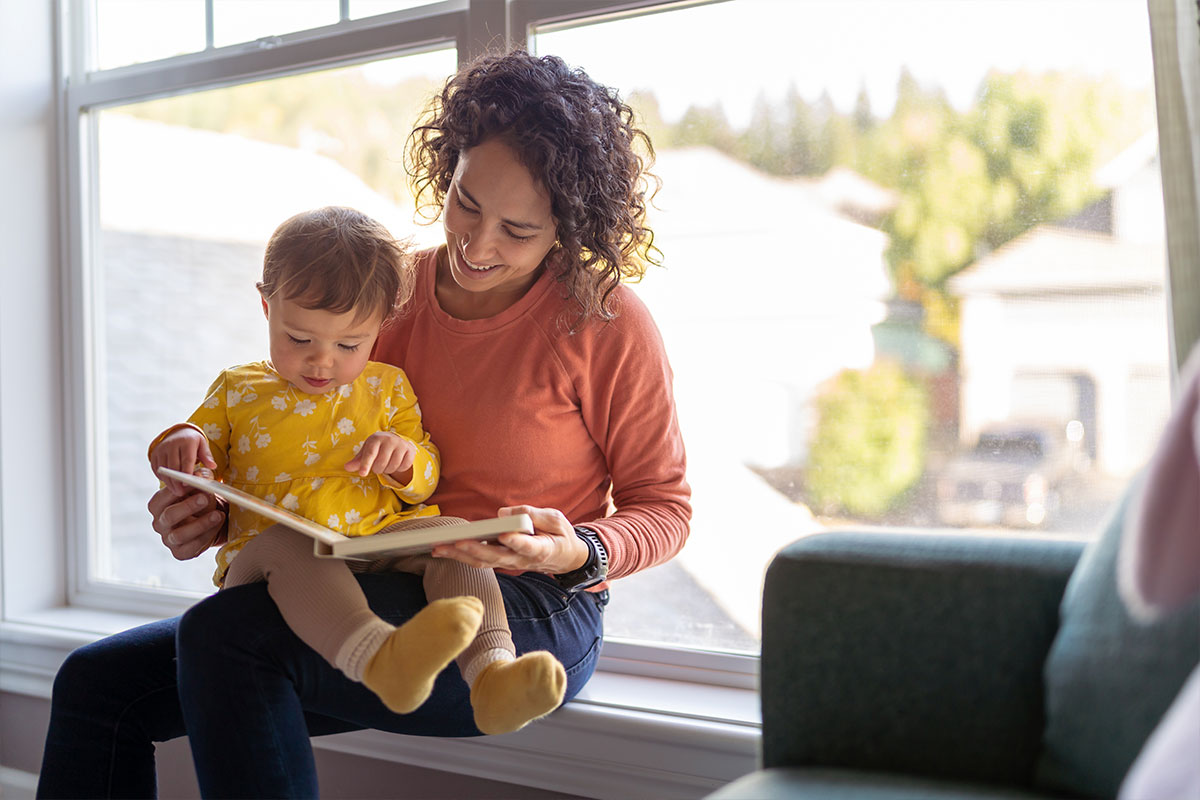 A mother reading a book to a small child on her lap