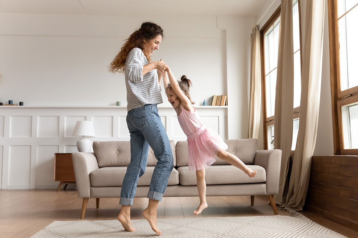 A mom and daughter dancing in a living room