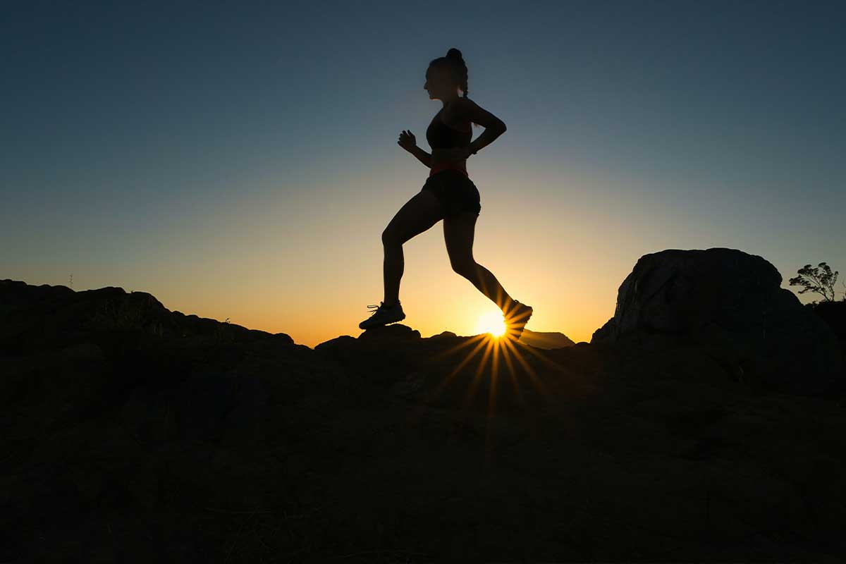 A woman trail running at sunset