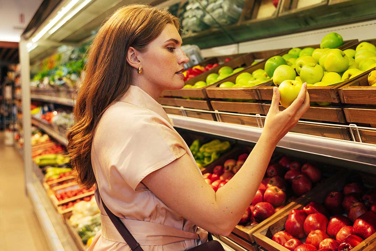 A woman inspecting produce in a grocery store