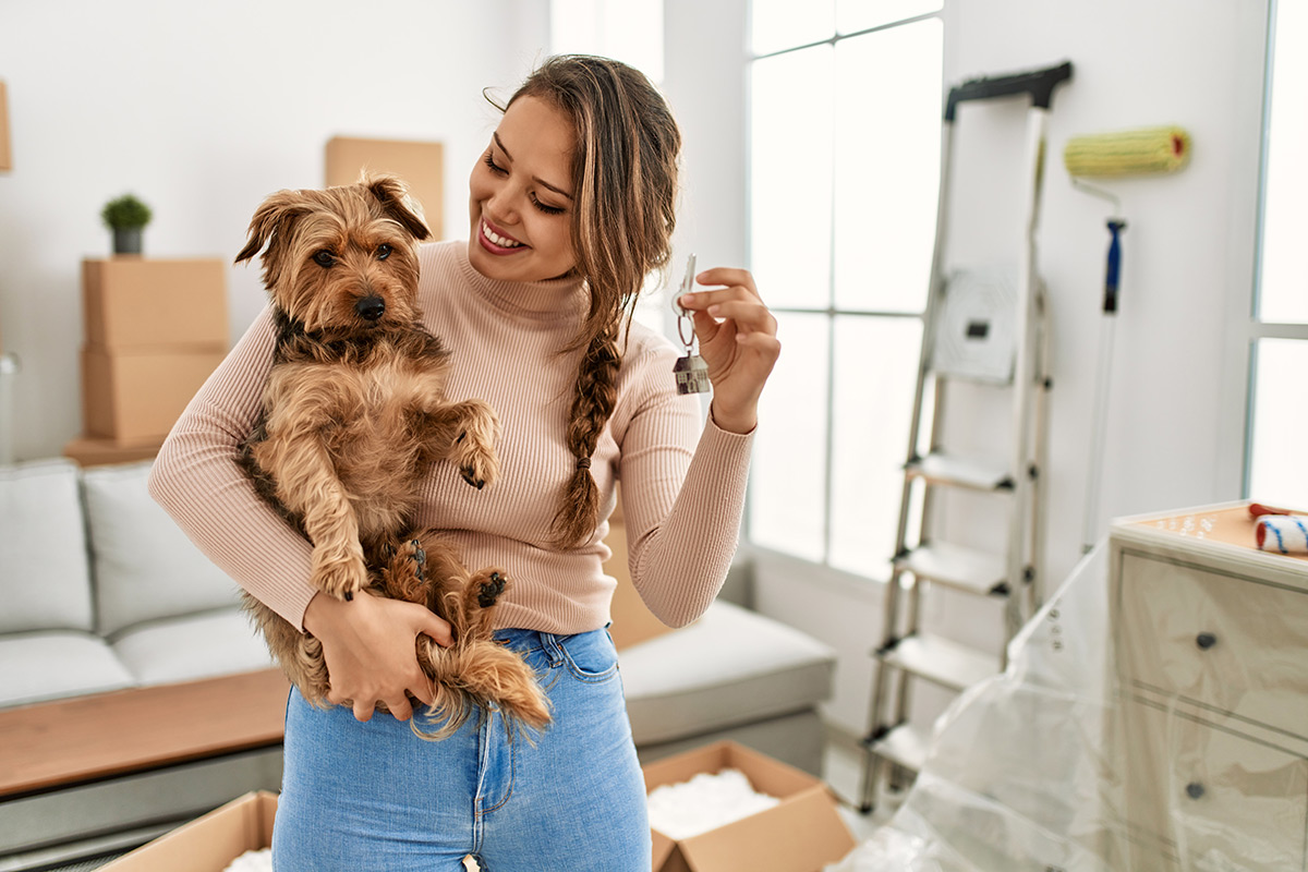Young homeowner holding her dog and her house keys
