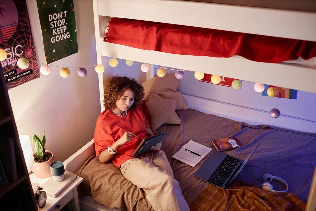 A college student laying in bed reviewing finances