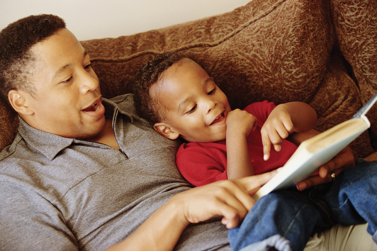 Father and son reading a book on the couch