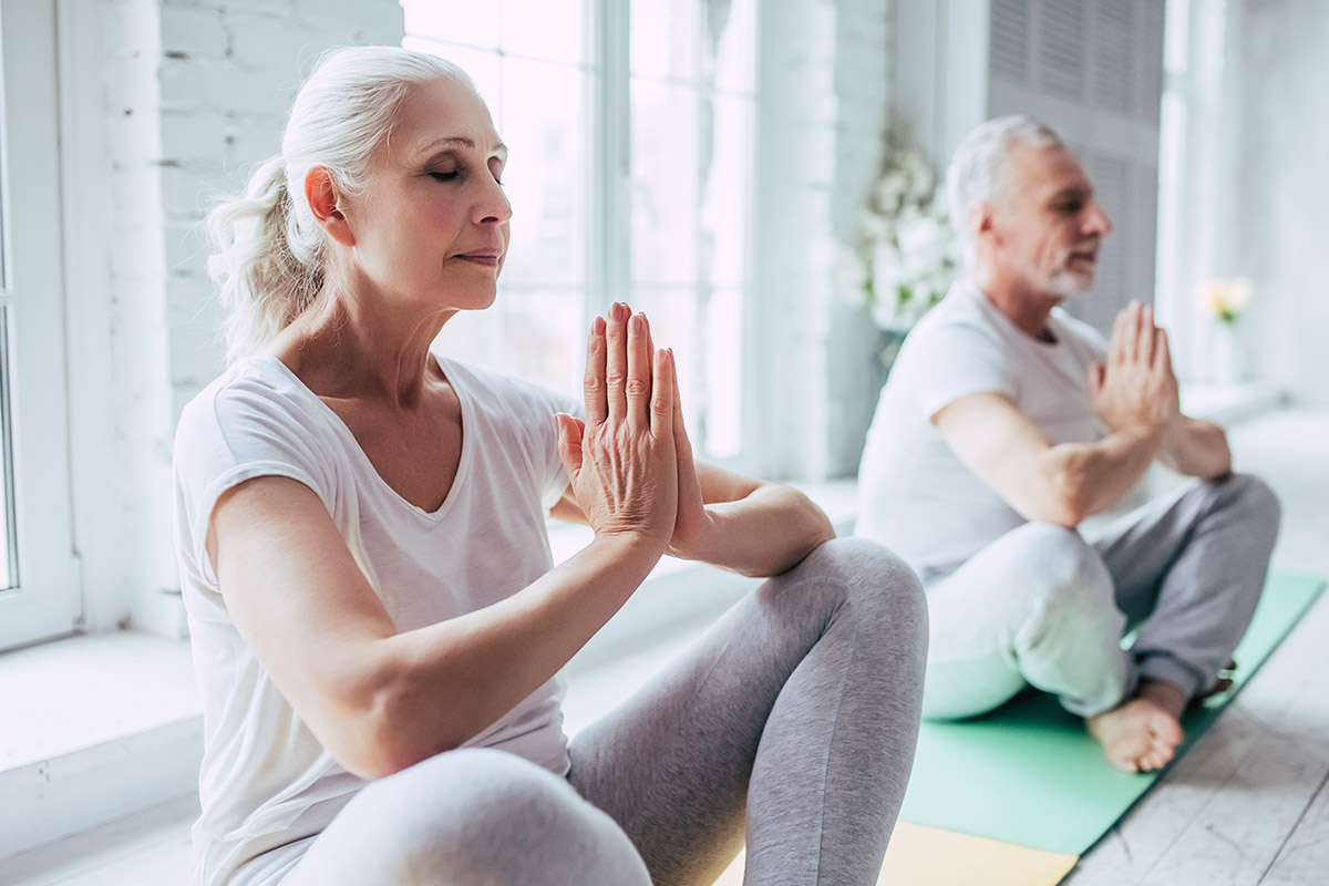 Senior couple is doing fitness training at home. Doing yoga together. Healthy lifestyle concept.