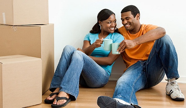Couple moving Couple drinking coffee as they sit on floor near moving boxes