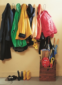 Coats hung on wall hooks and umbrellas in holder