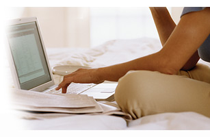 Women sitting in bed checking her credit score on a laptop