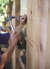 Hands hammering nail into wood