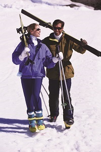 Couple carrying skis in the snow
