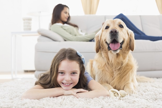 A girl and her dog lying on the floor in front of a woman lounging on the couch