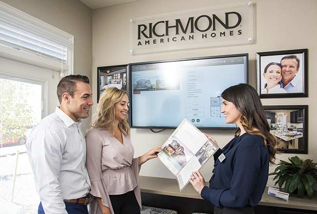 Sales associate speaking with homebuyers at sales center