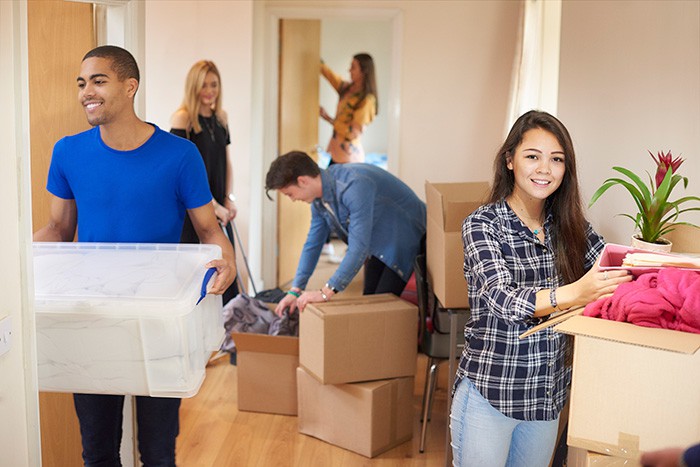 Several people packing boxes inside a house