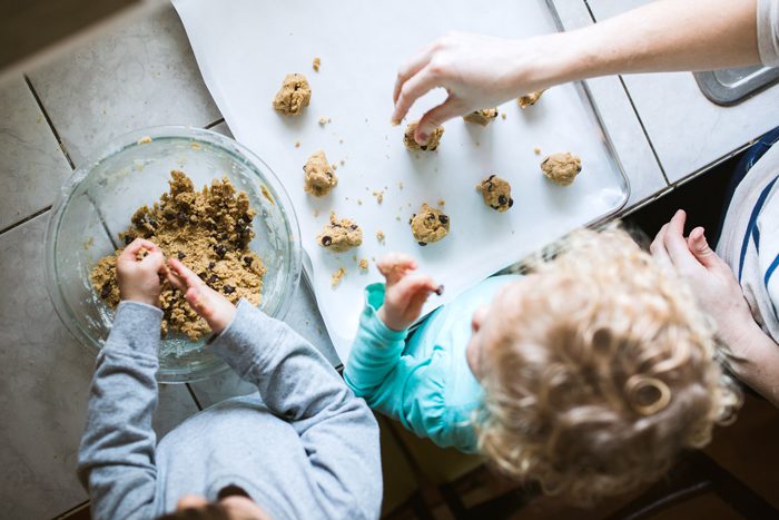 Kids putting cookie dough onto a baking sheet