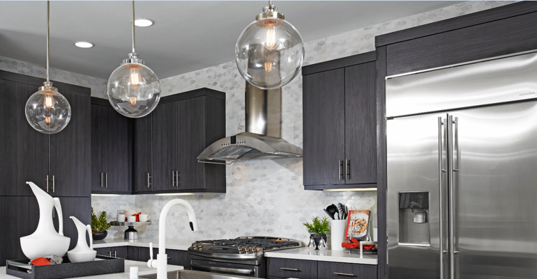 Three round glass pendant lights in kitchen with dark cabinets