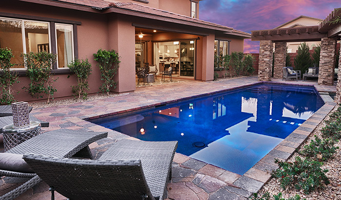 Covered patio, pool and lounge chairs in backyard