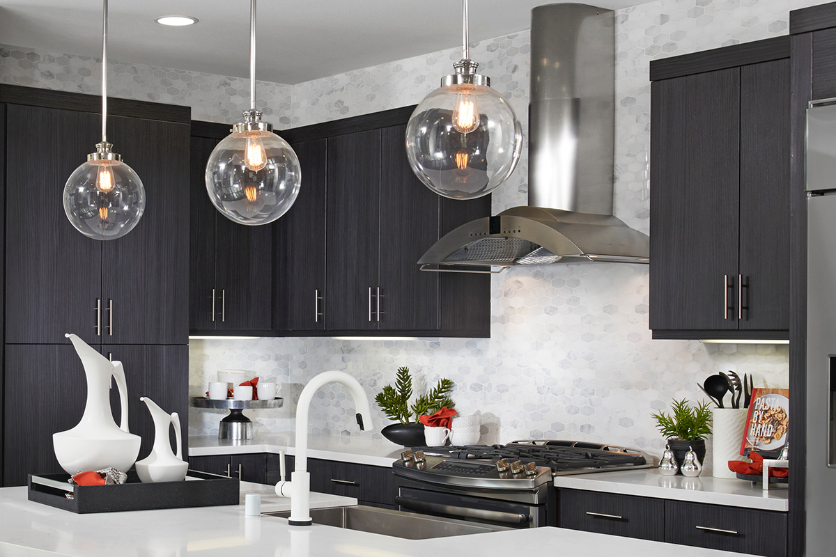 Penn pendant lights over island in kitchen with dark cabinets and light countertops