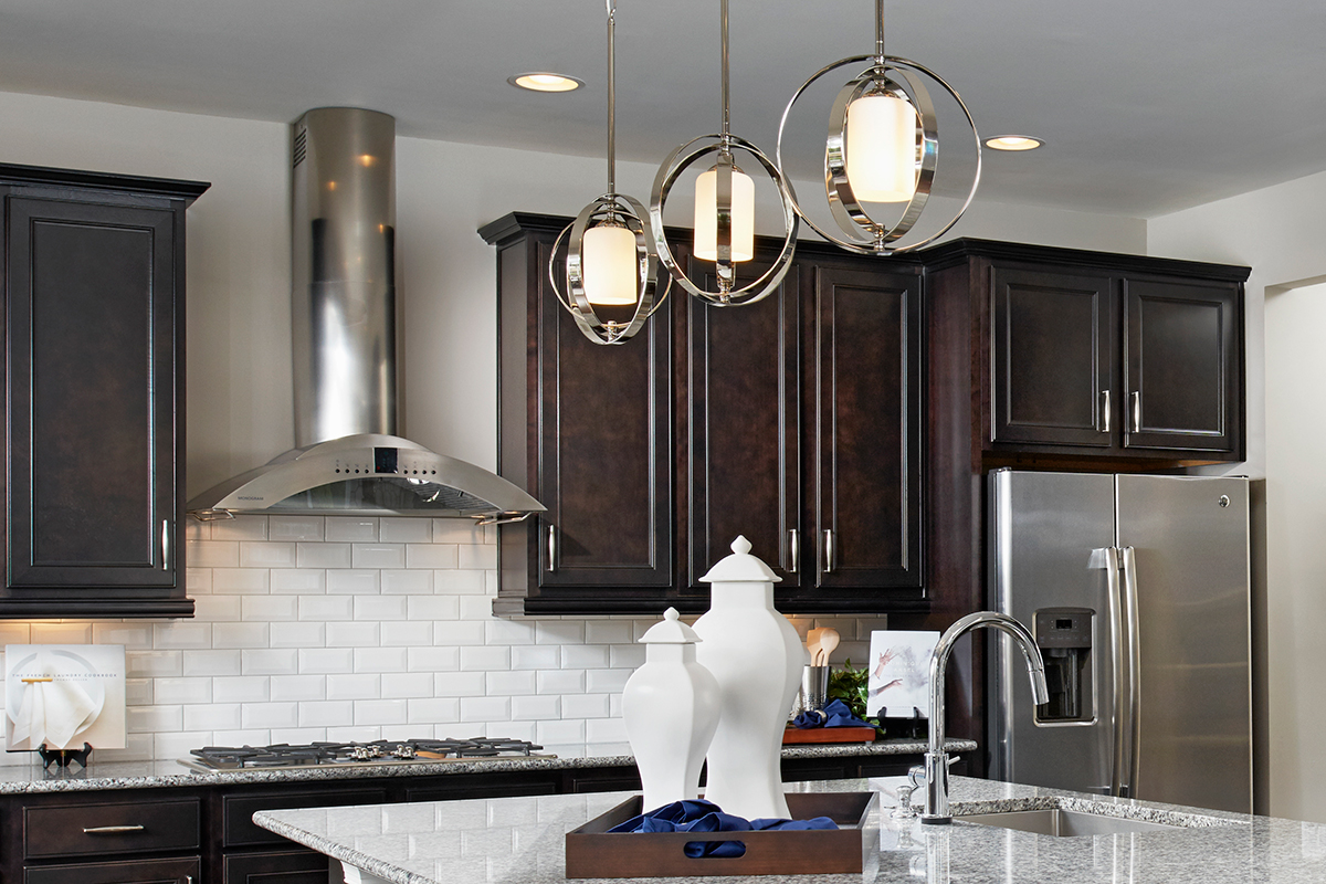 Equinox pendant lights over island in kitchen with dark cabinets and white subway tile backsplash