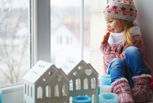 Girl sitting on window sill looking at two small white model houses