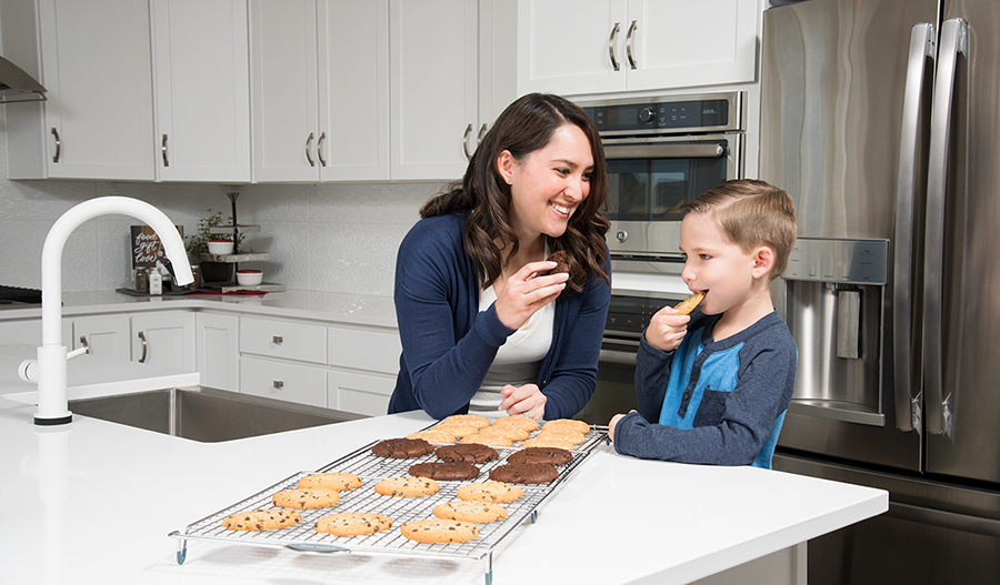 Mother and son baking cookies in kitchen with white cabinets and center island