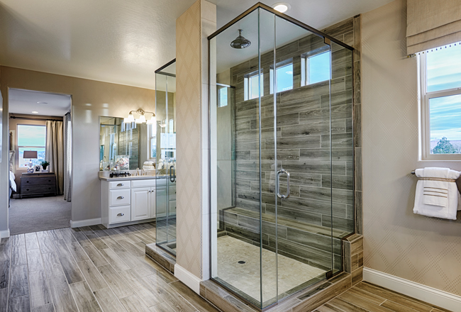 Frameless glass shower with tiled wall and bench in primary bathroom of Sage home